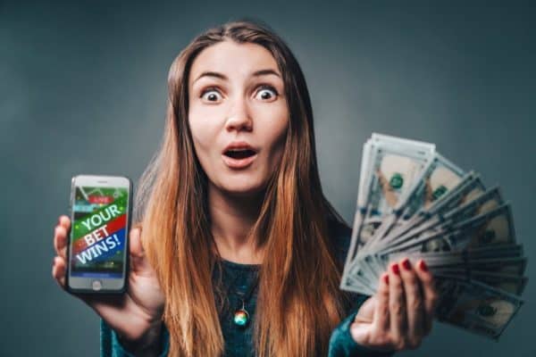 woman being happy winning a bet using a sports betting app on her phone